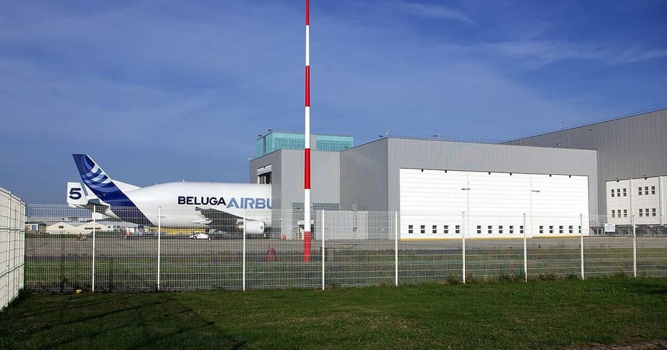 Airbus Beluga timber carrier aircraft stands in front of the hangar building at the airport.