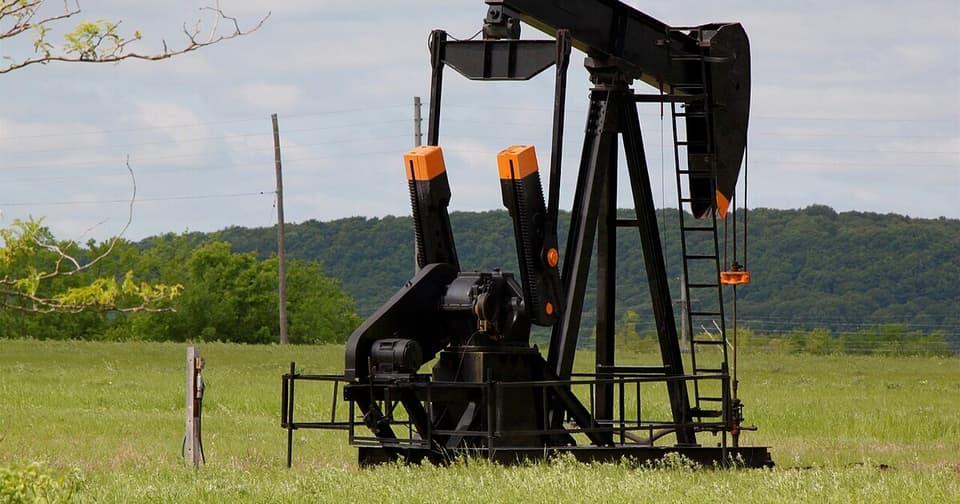 Black oil pump jack in a green meadow
