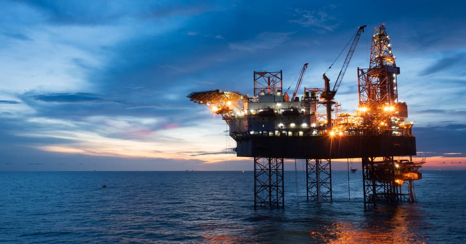 Offshore oil drilling platform illuminated at night in the middle of the sea