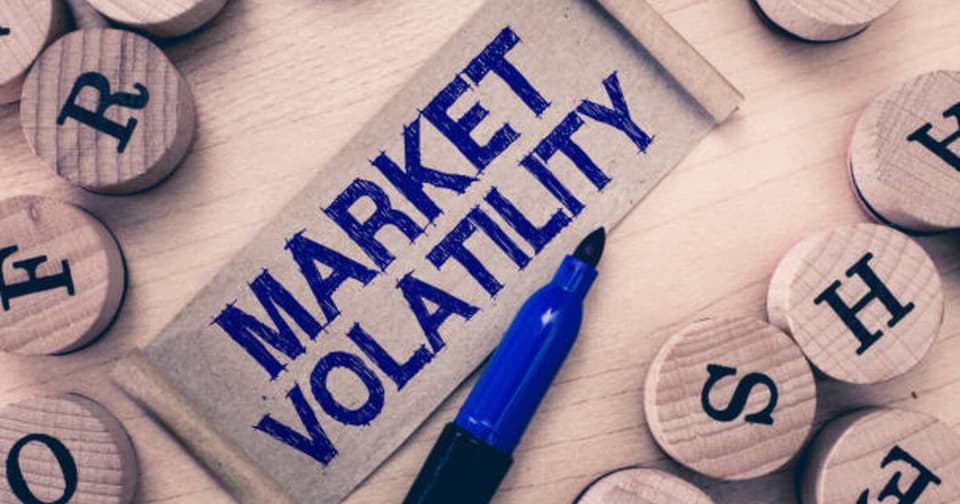 Wooden blocks representing market volatility and MARKET VOLATILITY text written with a blue pen
