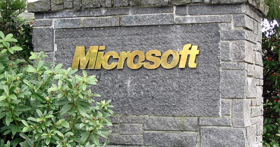 The yellow-gold logo of Microsoft on the stone wall of its corporate building.
