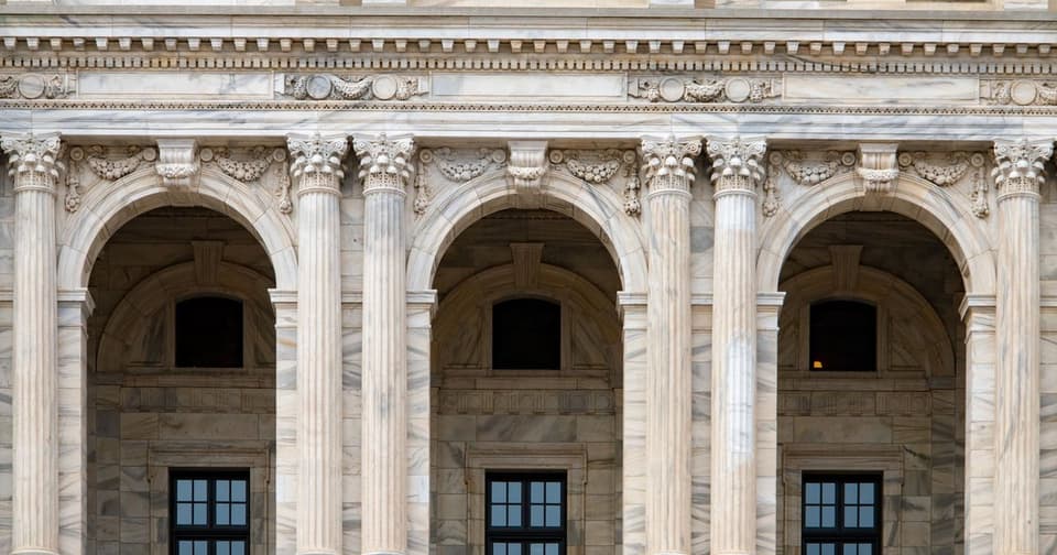 Facade of a marble building with arched windows and carved Corinthian columns