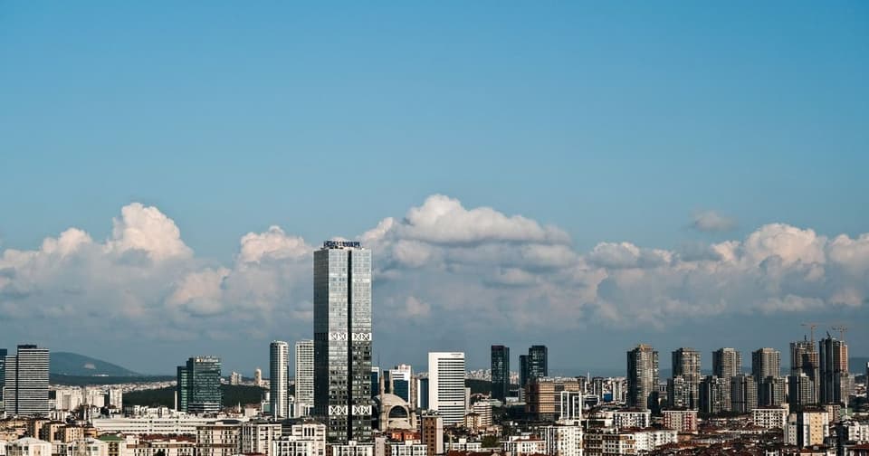 Skyscrapers rising amid dense urban development under a blue sky with white clouds