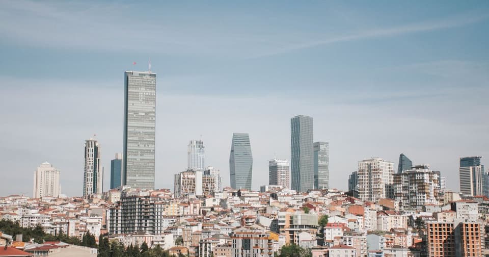 Glass skyscrapers rising above a city of low-rise buildings under an open sky